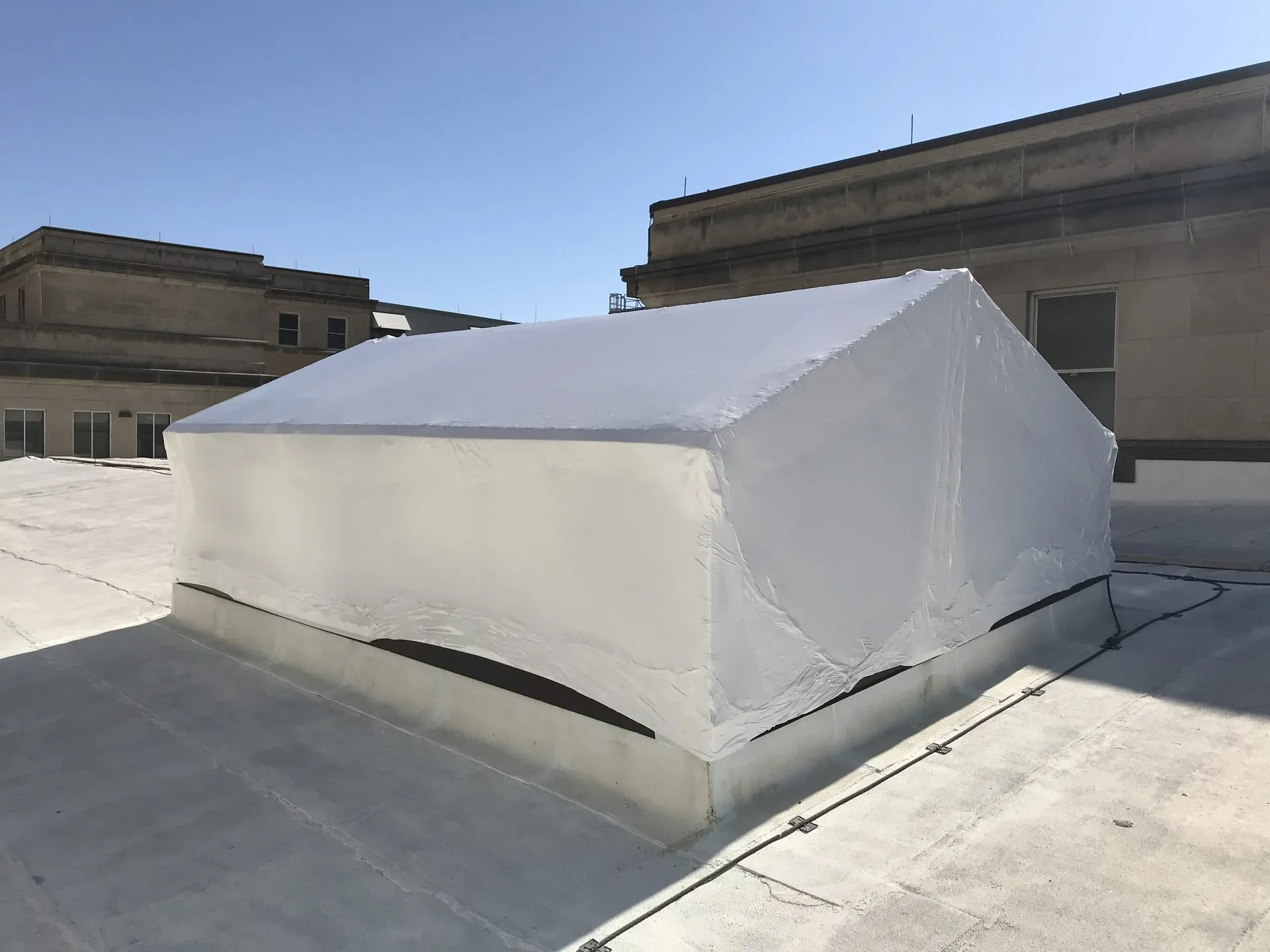 Rooftop HVAC unit shrink wrapped for protection at a USPS facility